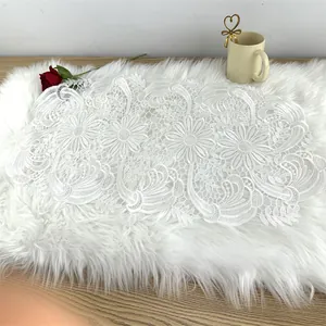 Detailed view of white water-soluble floral lace table runner on faux fur