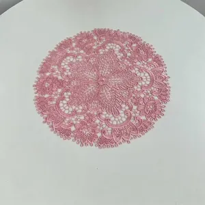 Pink round embroidered lace placemat with intricate floral patterns for table decor.