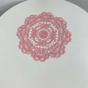 Detailed macro shot of pink embroidered floral lace coaster with scalloped edges