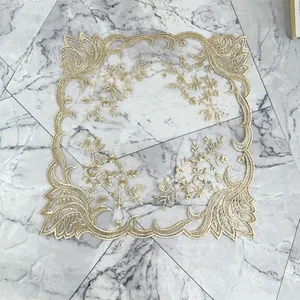 Primer plano de un mantel individual de encaje bordado en oro con delicados motivos florales