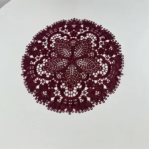 Detail view of intricate burgundy lace placemat with floral embroidery and cut-outs