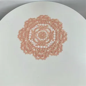 Detailed view of intricate lace embroidery on a rose gold round polyester table mat.