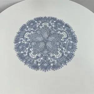 Detailed view of a blue embroidered lace placemat with intricate hollow patterns