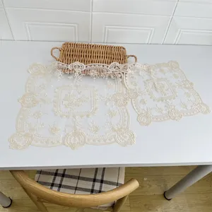 Detail der klassischen europäischen beigen Spitzen-Tischsets mit feiner Blumenstickerei auf Tisch.