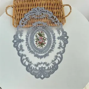 Detailweergave van ovale kanten placemat met vintage bloemenborduurwerk en schulpranden