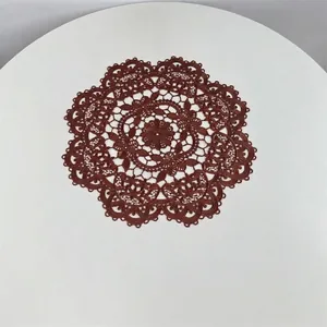 Detailed view of dark brown embroidered hollow lace round placemat on white table