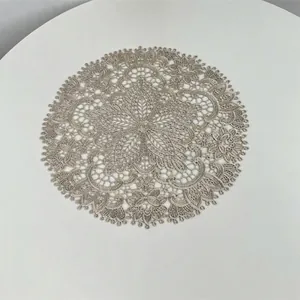 Detailed view of intricate floral lace embroidery on circular beige doily