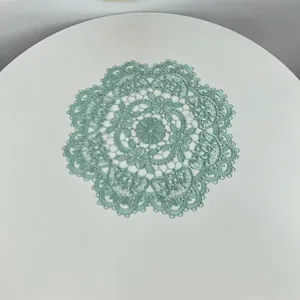 Detailed view of a mint green round embroidered lace placemat with floral pattern.