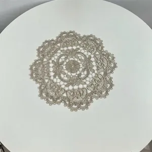 Macro view of detailed floral embroidery on a vintage-style hollow-out lace coaster