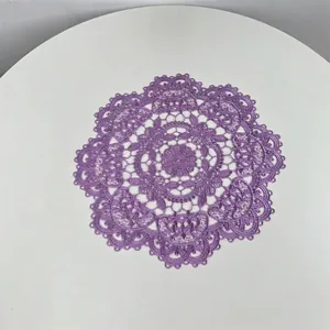 Close-up detail of a purple circular embroidered lace placemat with floral pattern