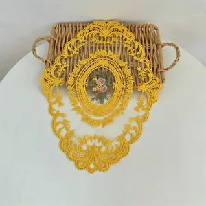 Gedetailleerd overzicht van geel geborduurde kant placemat met bloemmotief op rieten dienblad
