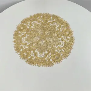 Detail view of a golden embroidered lace placemat with intricate vintage floral and lattice patterns