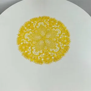 Detailed top view of a yellow embroidered lace placemat with intricate patterns.