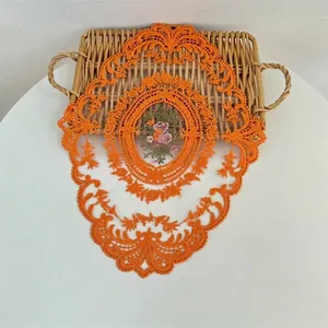 Detailweergave van een oranje geborduurde kanten placemat op een rijk gevlochten dienblad
