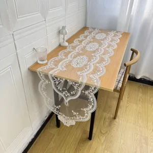 Elegant white lace table runner with intricate floral embroidery on wooden table