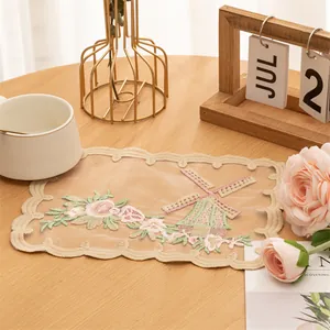 Elegant vintage lace coaster with embroidered floral and windmill design on table