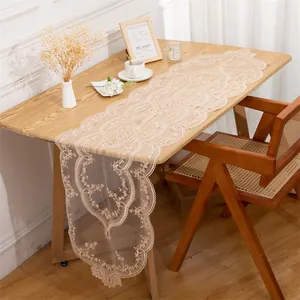 Detail view of an elegant beige lace embroidered table runner on a wooden dining table