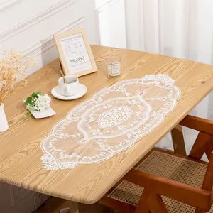 Detailed view of elegant white lace embroidered table runner with intricate floral cutouts
