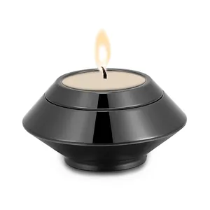 Close-up of a lit candle inside a black stainless steel cremation memorial urn
