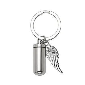 Macro detail of stainless steel cylindrical cremation urn keychain with rose wing charm