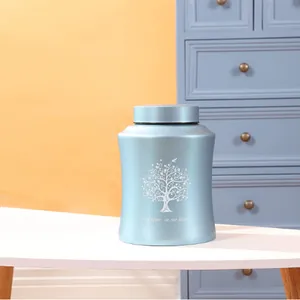 Close-up of a blue memorial urn with Tree of Life engraving on a white table