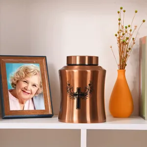 Copper pet urn with winged cross engraving in a commemorative home setting