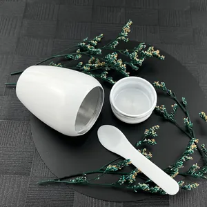 Macro view of a white capsule-shaped memorial urn with a matching lid and spoon set