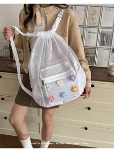 Modelo asiática con mochila de malla blanca decorada con flores de ganchillo de colores