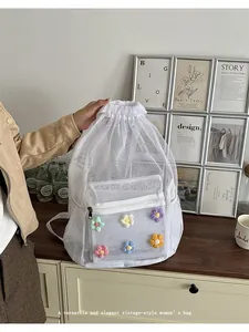 Detalle de una mochila de malla blanca con adornos de flores de punto coloridas