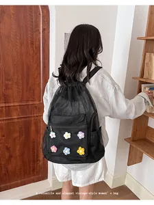Vista posterior de una mochila de malla negra con parches de flores en una modelo