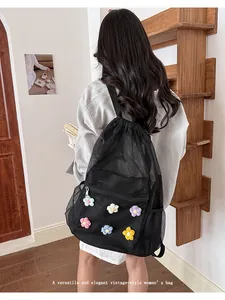 Vista trasera de una mochila de malla negra con decoraciones de flores tejidas a mano