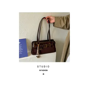 Detail einer retro braunen Wildleder-Baguette-Schultertasche mit Herzanhänger.