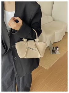 Vista dettagliata di una borsa a secchiello plissé beige retrò tenuta da una modella