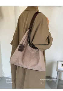 Detail einer großen hellbraunen Hobo-Tasche aus Wildlederimitat zu einem Trenchcoat