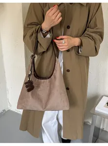 Nahaufnahme einer braunen Vintage-Wildleder-Umhängetasche mit einem m-Anhänger.