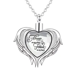 Close-up of a memorial heart urn necklace featuring angel wings and an engraved quote.