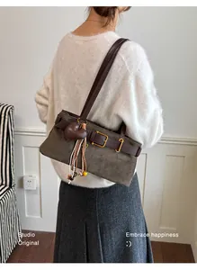 Detailansicht einer braunen Wildleder-Baguette-Tasche mit Herzanhänger und trendigen Fransen