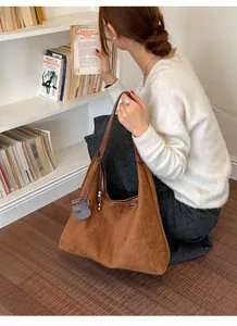 Braune Hobo-Tasche aus Wildlederimitat mit Webstruktur in einer Lifestyle-Buchhandlung
