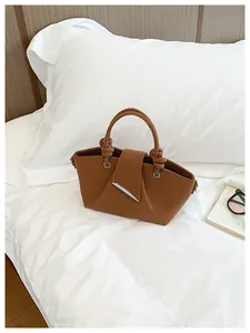 Elegante borsa a mano marrone plissettata retrò presentata su biancheria da letto