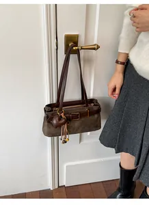 Nahaufnahme einer braunen Wildleder-Baguette-Tasche an einem Retro-Türgriff.