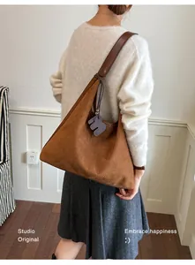 Detailansicht einer braunen Vintage-Hobo-Tasche aus Wildlederimitat über einem weißen Pullover
