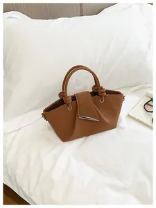 Borsa a secchiello retrò plissettata marrone con barra metallica su biancheria da letto.