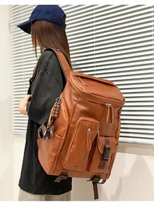 Detailed view of a large brown vintage faux leather backpack on model's shoulder