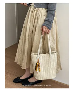 Detailansicht der cremeweißen geflochtenen Eimertasche mit Retro-Perlenanhänger