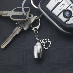 Detail of a stainless steel cremation urn keychain with a paw print charm on keys