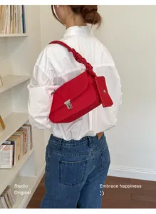 Dettaglio borsa a tracolla in nylon rosso con fibbia argentata e tracolla intrecciata.