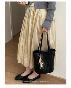 Detailansicht einer schwarzen gewebten Beuteltasche mit elegantem Perlenanhänger
