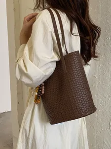 Elegante, dunkelbraune gewebte Beuteltasche mit langen Schulterriemen und Perlenanhänger.