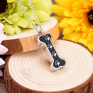 Close-up of bone-shaped stainless steel cremation pendant featuring paw print designs