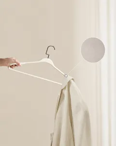 Primo piano della trama opaca antiscivolo di una gruccia color crema per abiti.